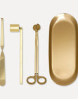 Premium gold candle care accessory set featuring a wick trimmer, candle snuffer, wick dipper, and matching oval tray on a clean background.