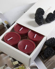 A deep purple blackberry scented tealight candle in a clear glass holder shown in the foreground with fresh blackberries resting on a partial view of the sliding box tray.
