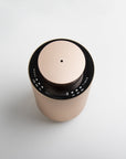 An overhead top-down perspective of the round rose gold diffuser, showing the central mist nozzle port and the black touch control panel surrounding the lid.