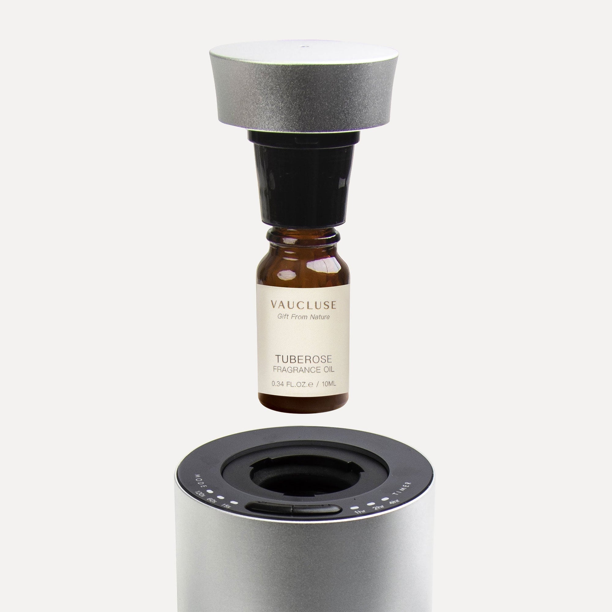 A step-by-step instructional shot of a 10ml tuberose esential oil bottle connecting to a black nozzle cap above a silver waterless diffuser.