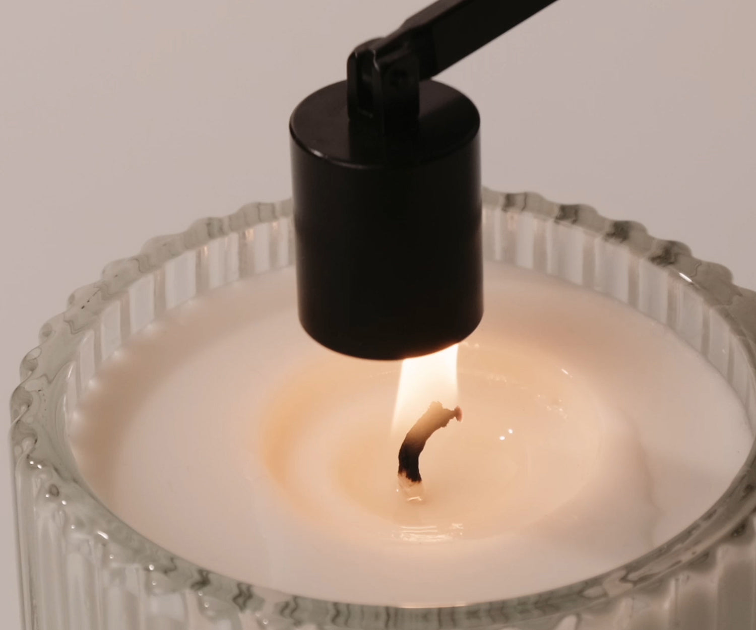 Using a black metal candle snuffer to properly extinguish a scented candle