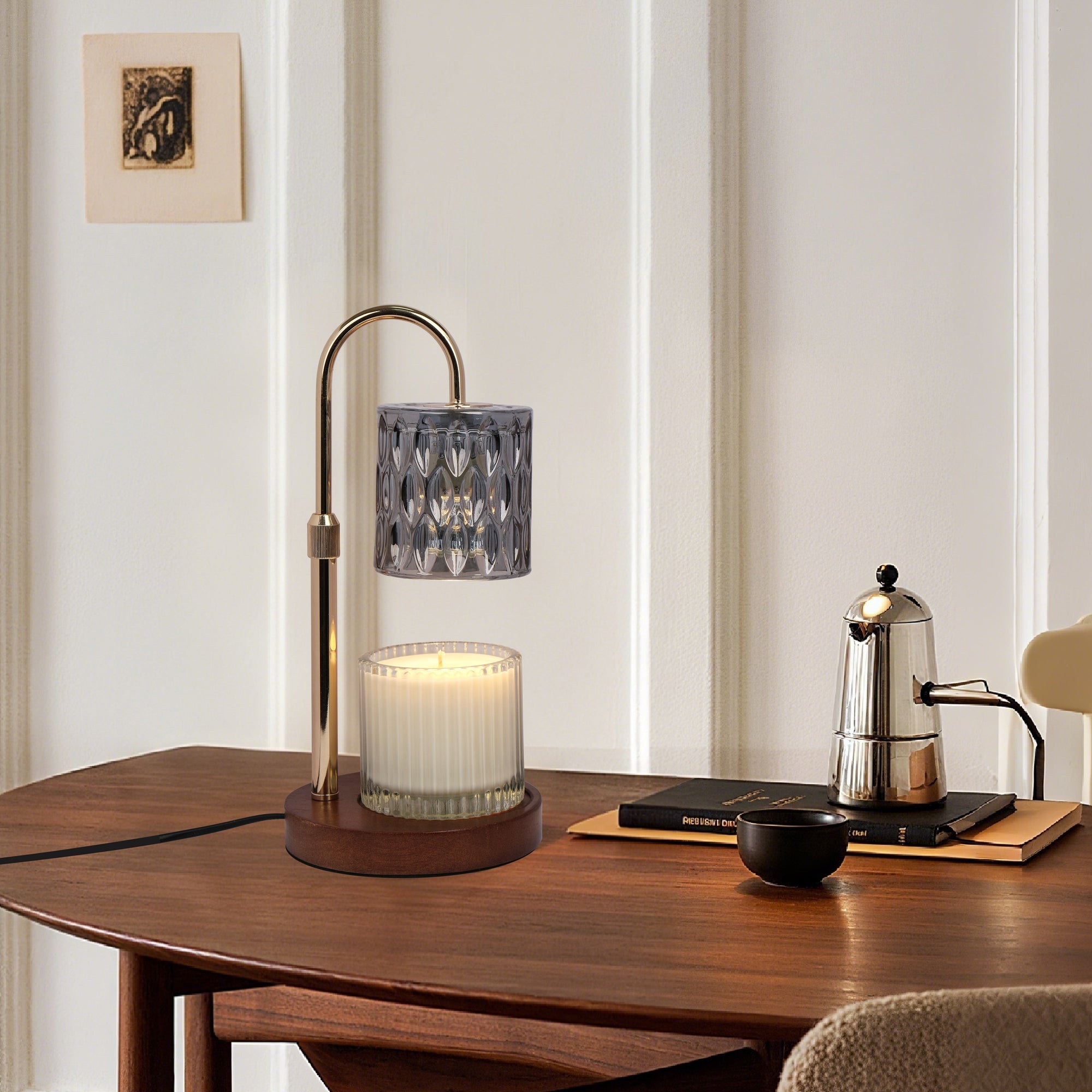 A lit smoky grey crystal candle warmer lamp casting ambient light over a jar candle on a dark wooden table next to a silver coffee moka pot.