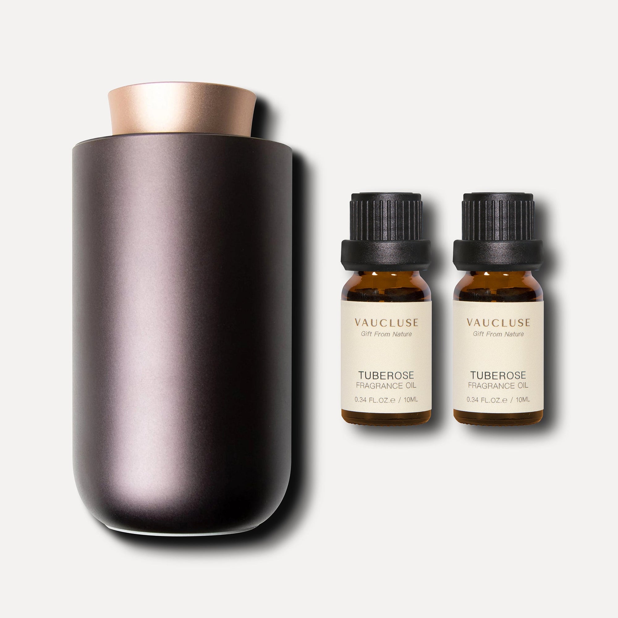 A metallic bronze waterless nebulizing aroma diffuser displayed next to two 10ml amber bottles of vaucluse tuberose essential oil.