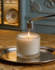 A classic silver bell candle snuffer being used to safely extinguish a burning candle flame on a luxury dining table setting.