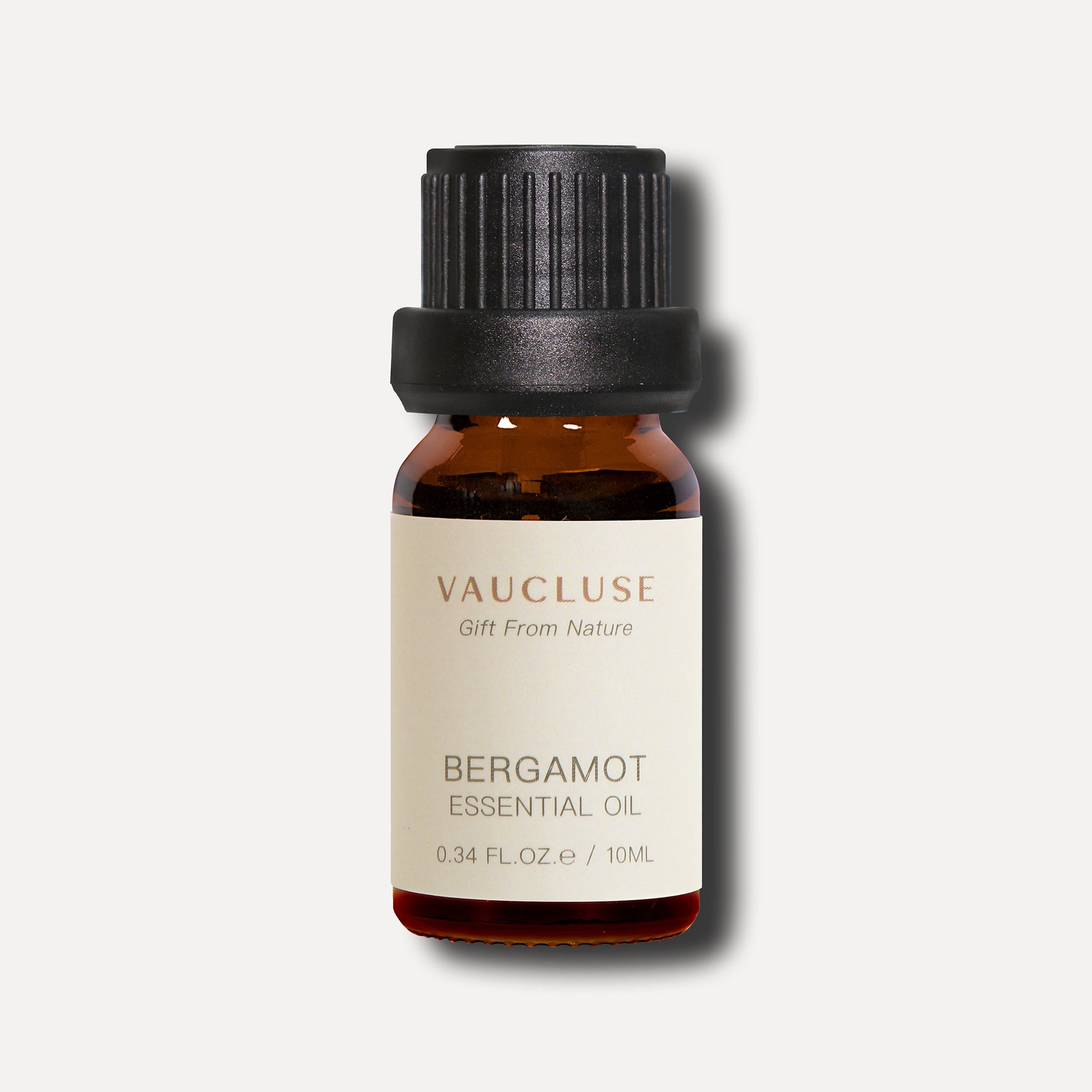 A minimalist e-commerce studio shot of a 10ml amber glass bottle of Vaucluse Bergamot Essential Oil with a black ribbed cap.