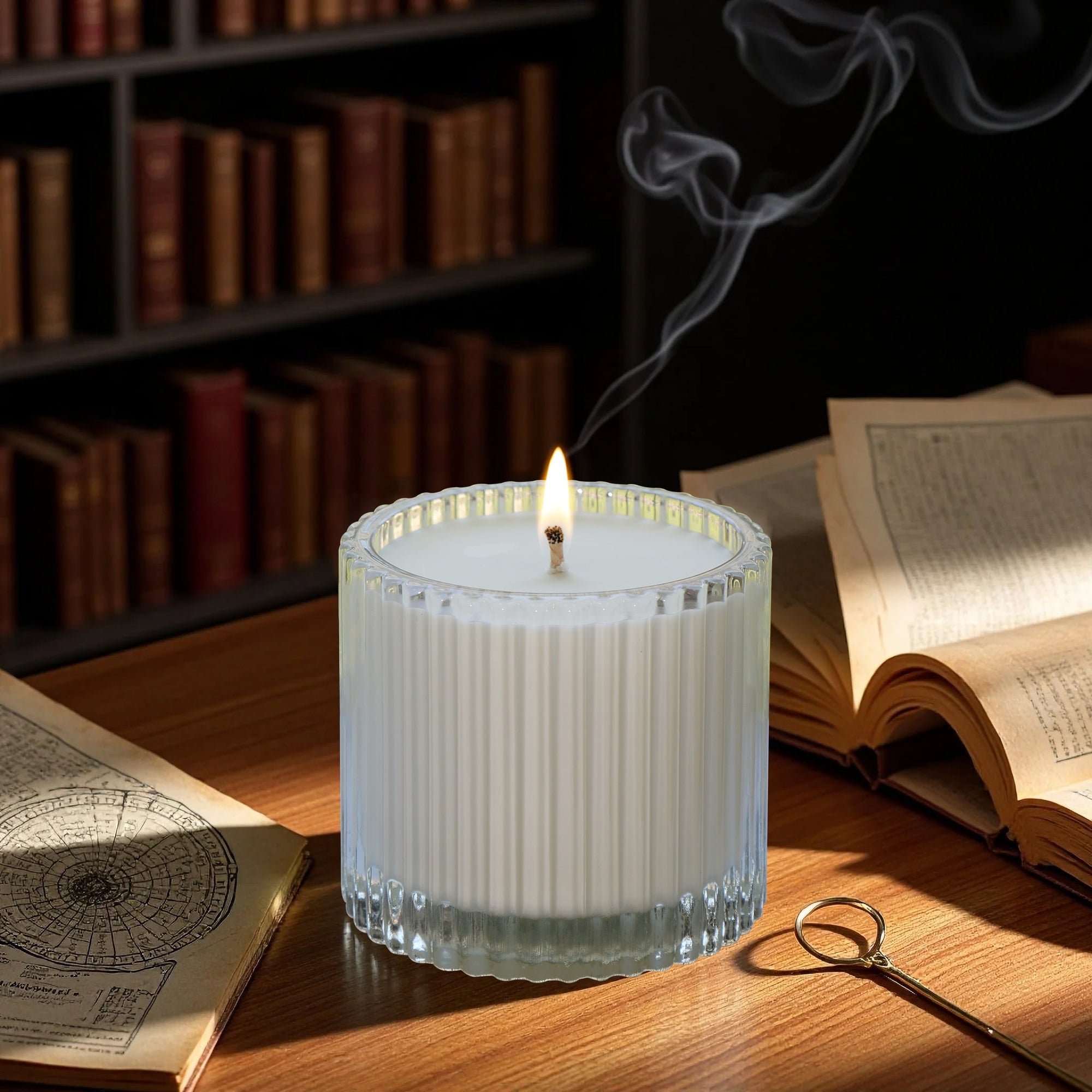 A lit Vaucluse Black Rose luxury scented candle with trailing smoke, resting on a warm wooden desk next to vintage books.