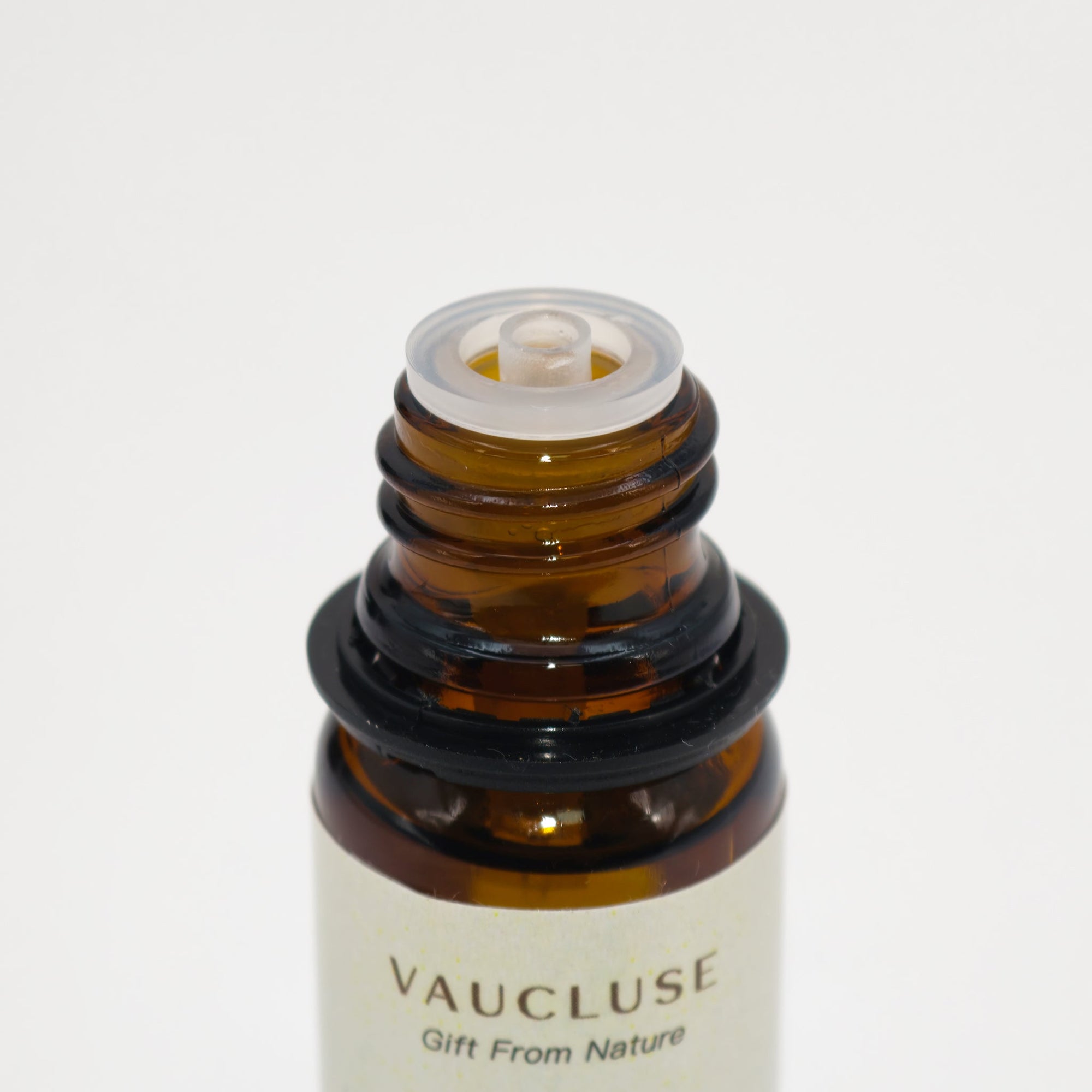 Macro close-up of the built-in dropper reducer cap on a Vaucluse essential oil amber glass bottle.