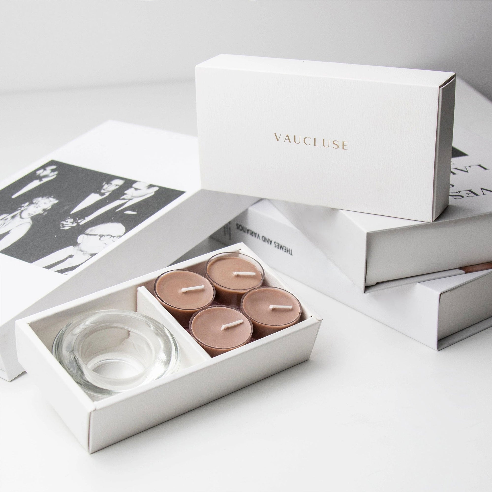 Premium unboxing scene showing the open cinnamon candle holder set placed against a neat arrangement of stacked white gift boxes with gold branding.