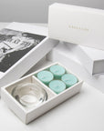 High-end unboxing presentation featuring the open ocean tealight candle set arranged with stacked white luxury gift boxes and an editorial book.