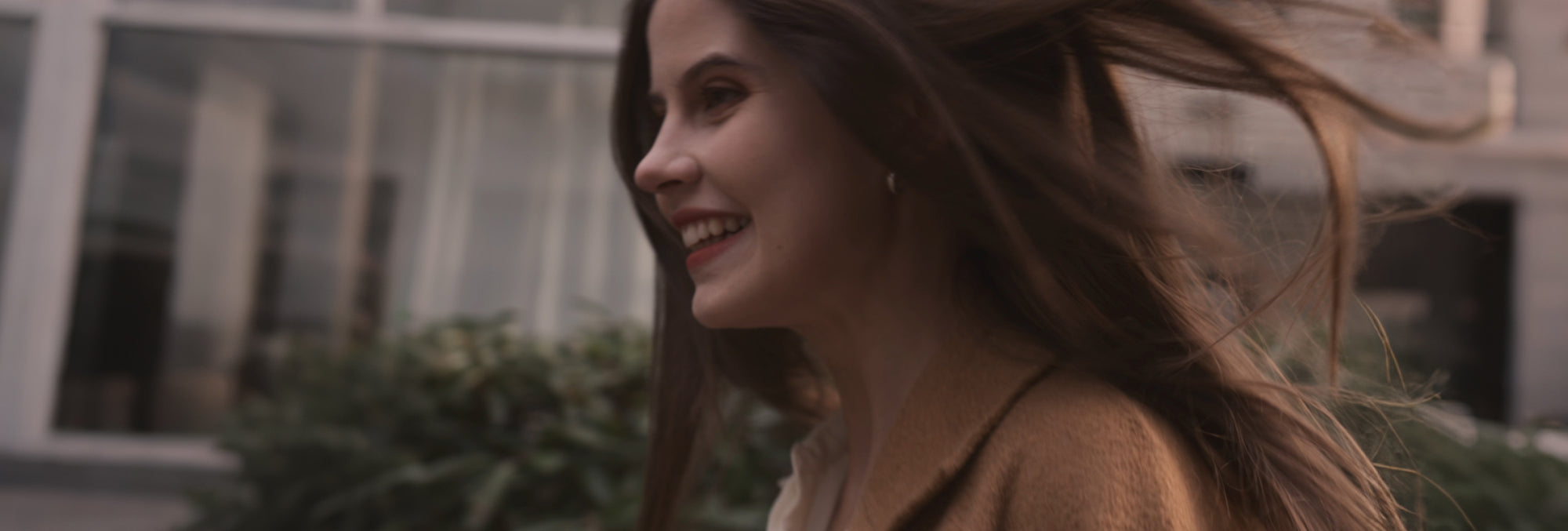 Smiling woman walking outdoors wearing a brown coat, representing the Vaucluse Fragrance story and brand origin.