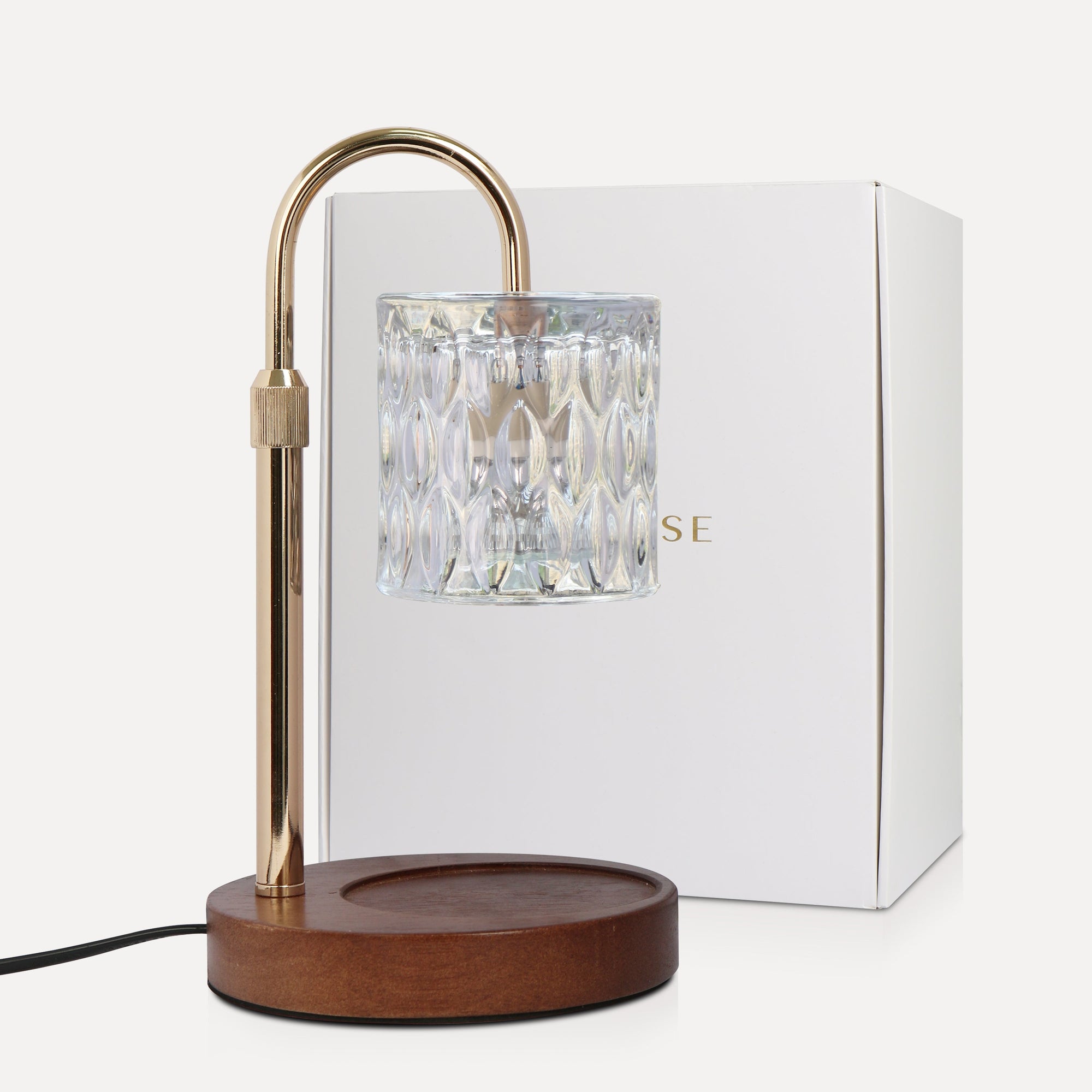 Vaucluse Fragrance premium transparent crystal candle warmer lamp with a clear glass shade, curved gold neck, and dark wood base sitting next to its white brand box.