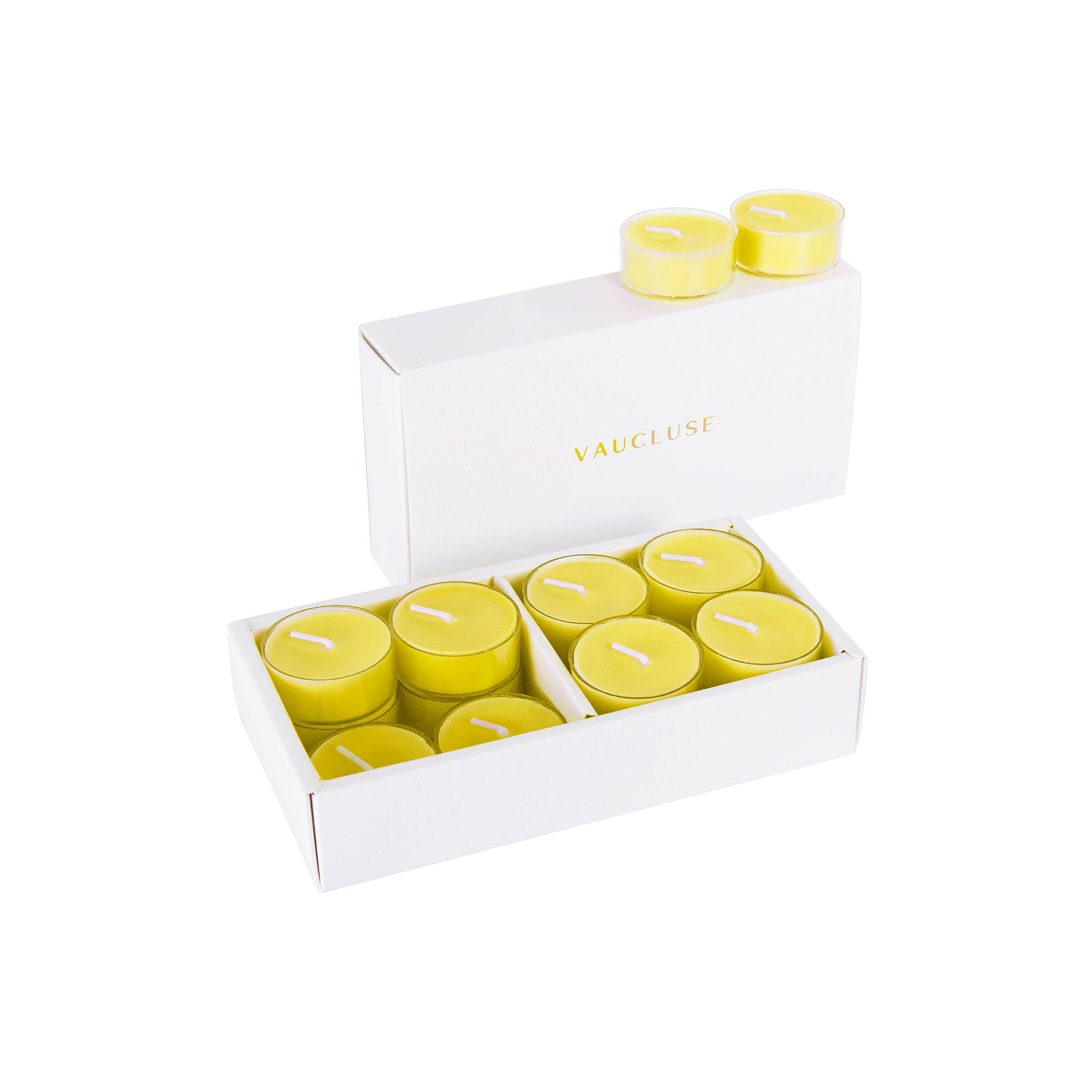 An open luxury white Vaucluse gift box displaying a set of bright yellow lemon scented tealight candles.