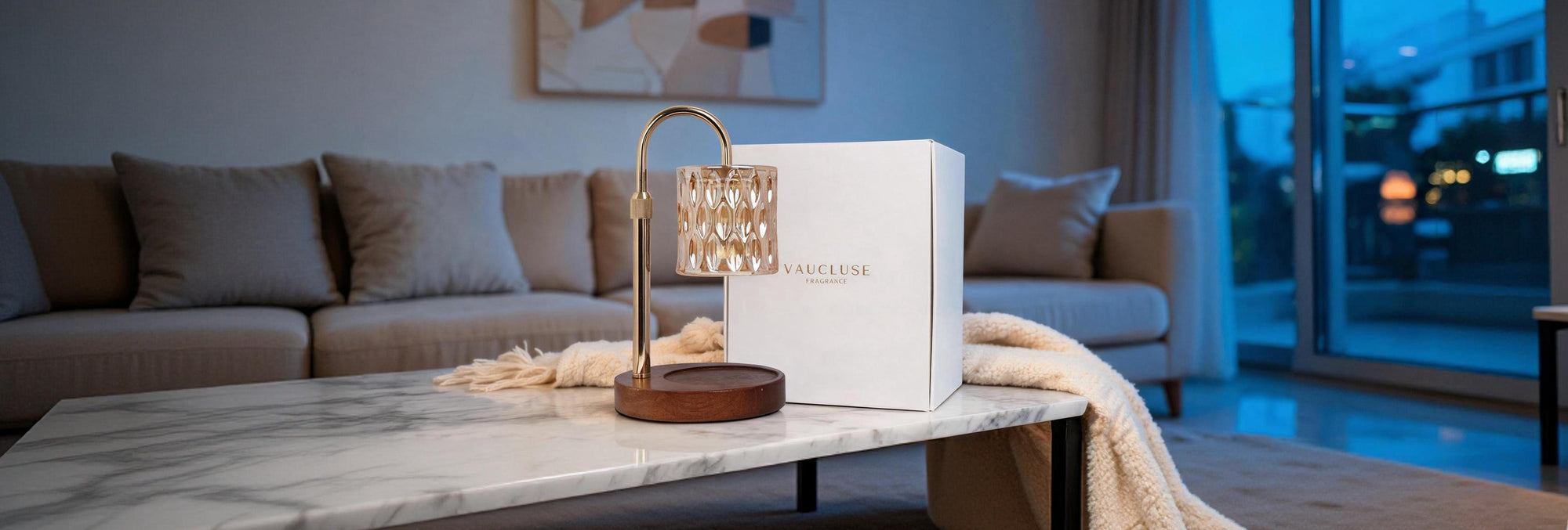 Vaucluse crystal candle warmer lamp with wooden base next to a luxury gift box on a marble coffee table.