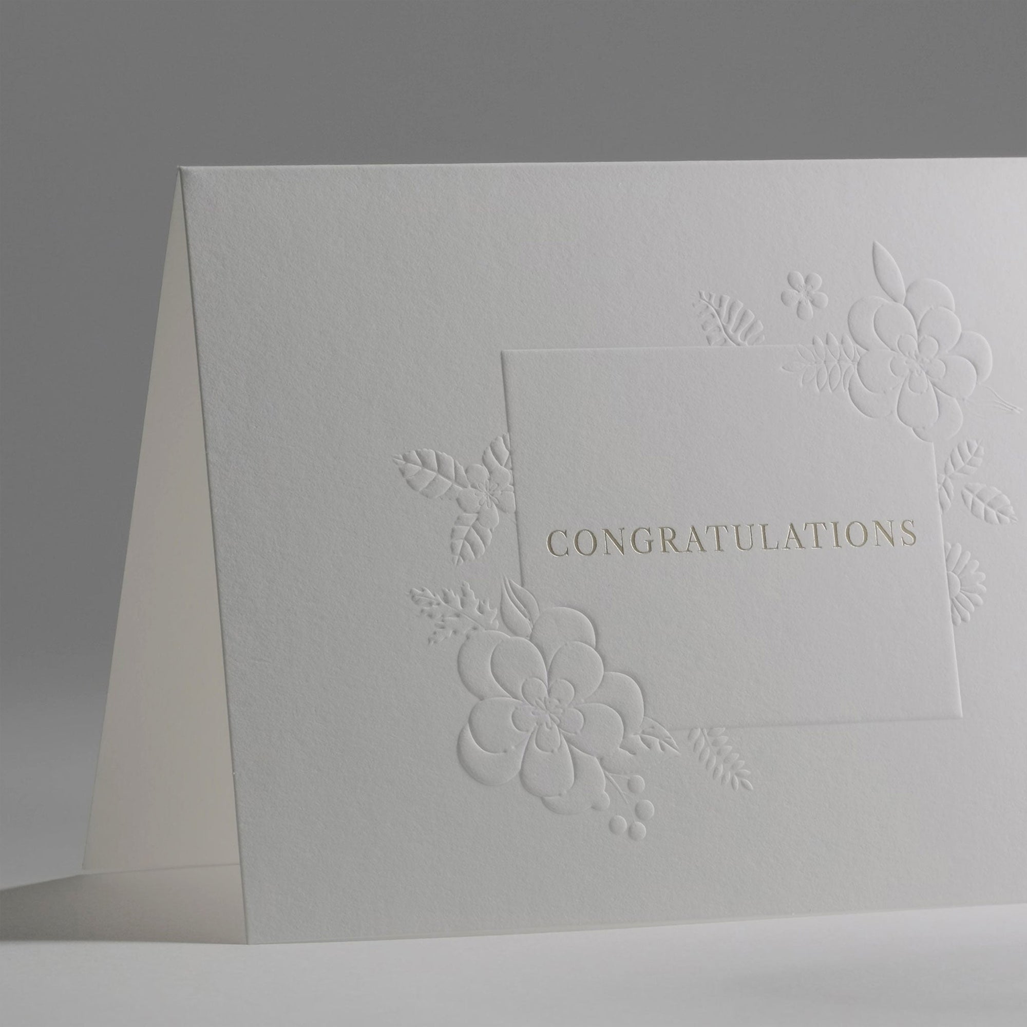 A detailed angle view showcasing the delicate blind-embossing technique and clean white paper stock used for the congratulations card.