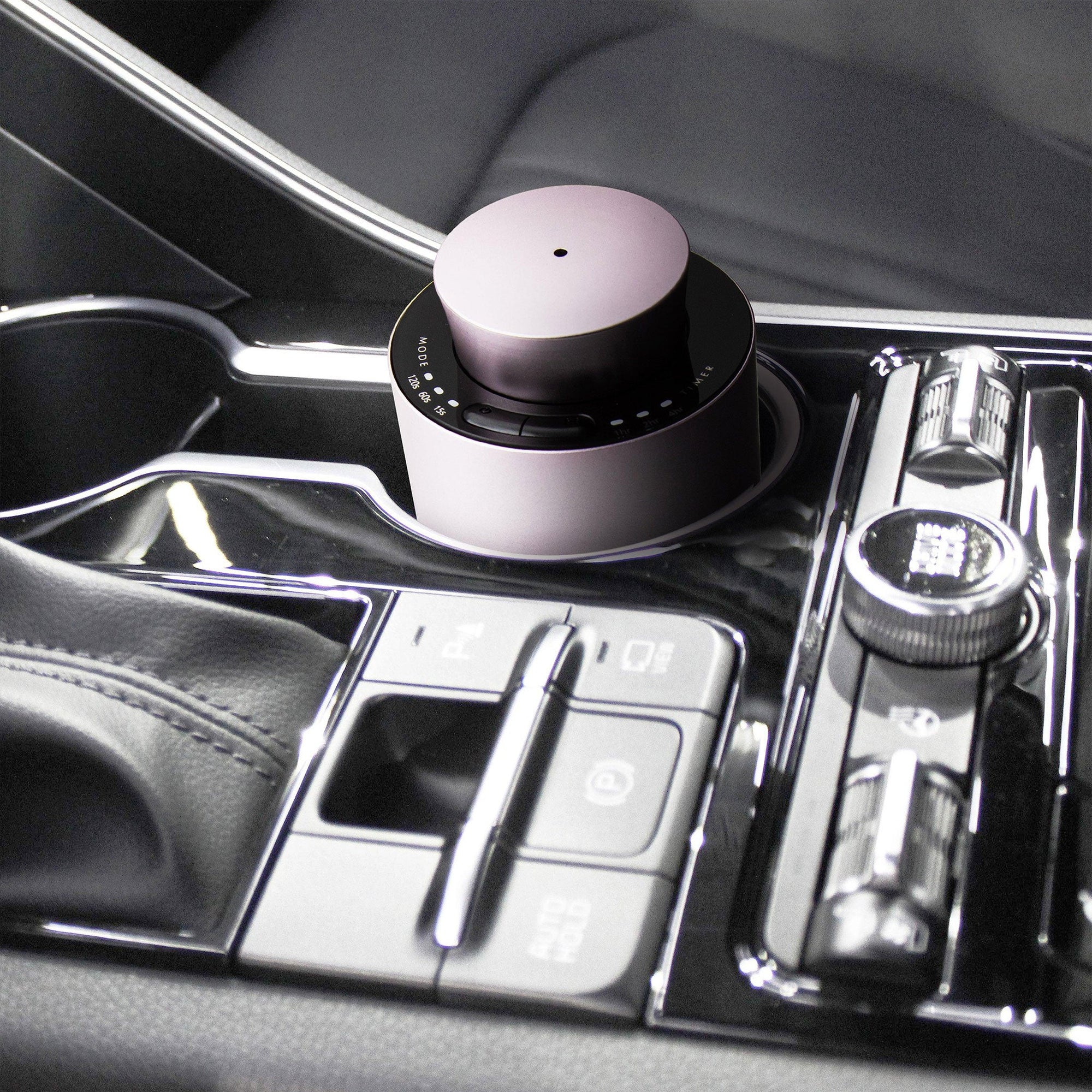 A portable purple dusk electronic diffuser positioned securely in a modern vehicle’s center console cup holder for car aromatherapy.