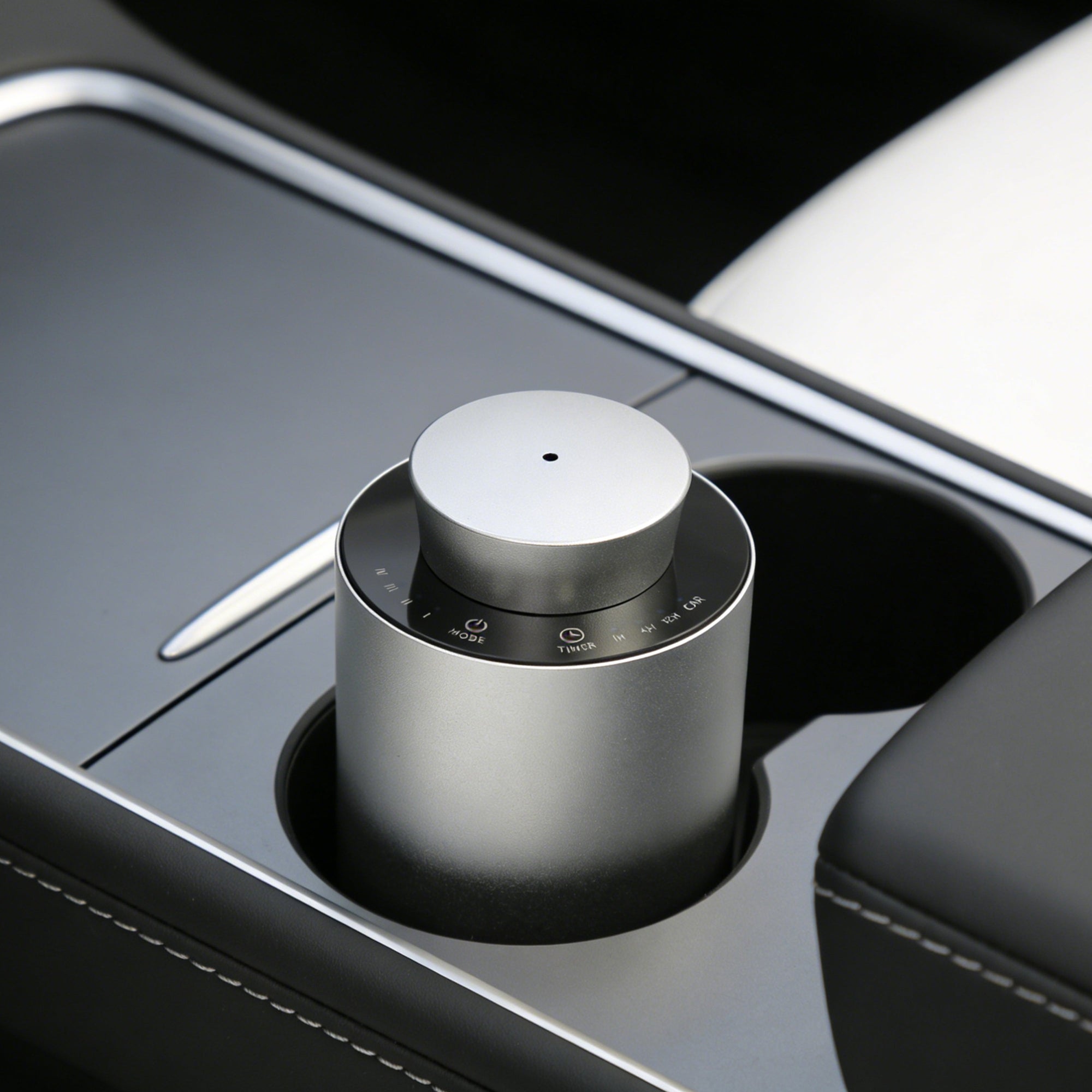 A portable silver electronic diffuser fitted neatly inside the center console cup holder of a car for on-the-go aromatherapy.