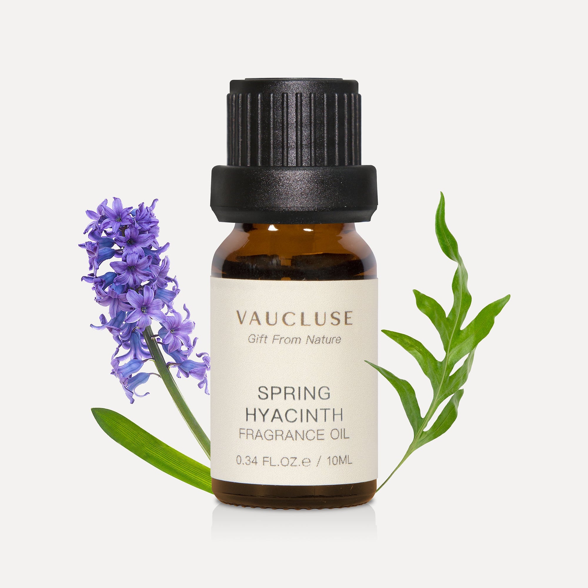 A 10ml amber glass bottle of Vaucluse Spring Hyacinth Essential Oil, flanked by a purple hyacinth flower stalk and a green serrated leaf.