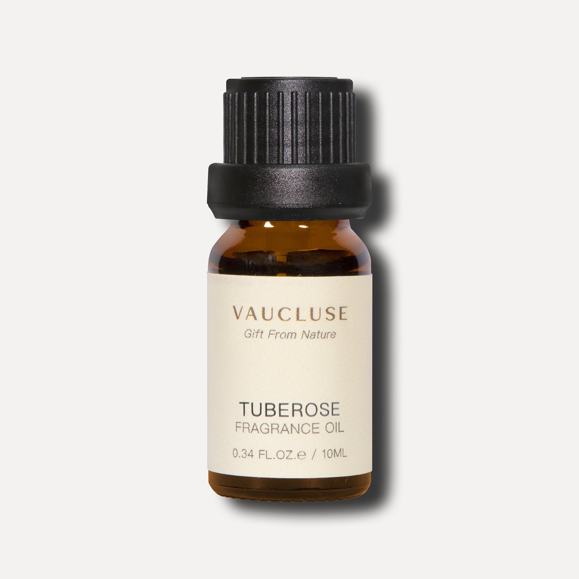 A clean front view studio shot of a 10ml amber glass bottle of Vaucluse Tuberose Essential Oil with a textured black cap.