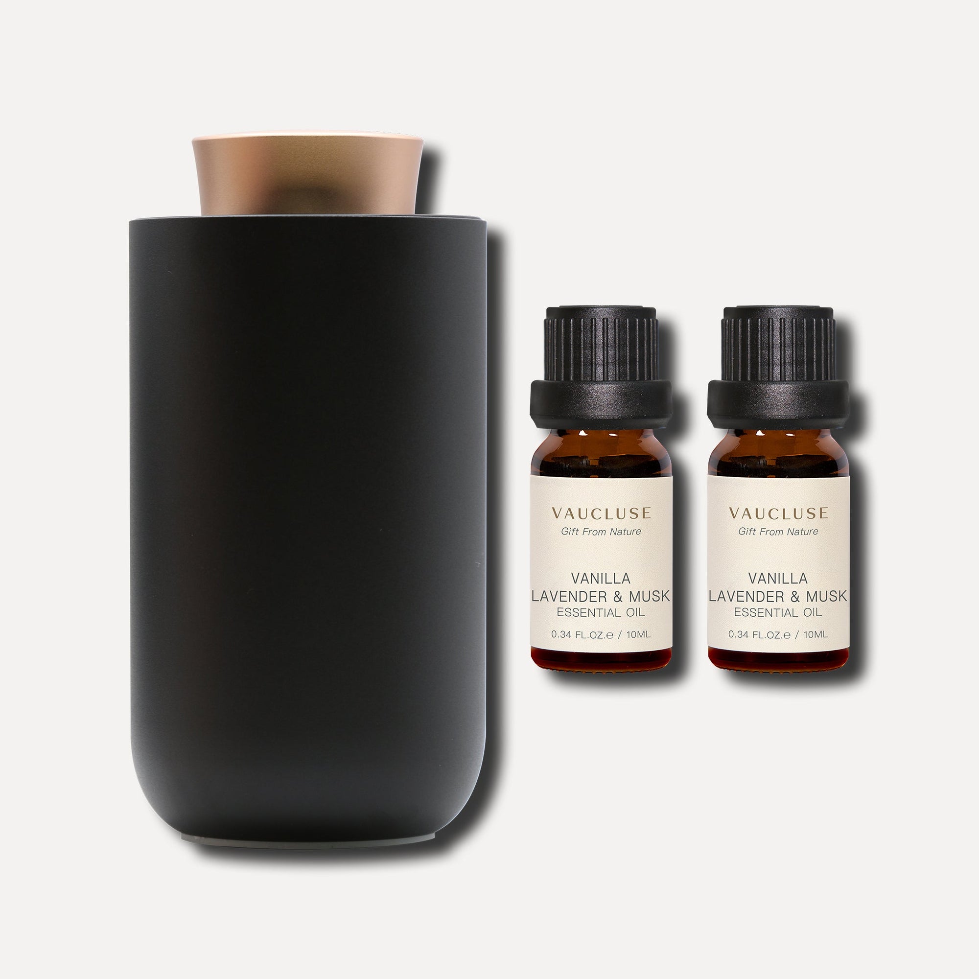 Two 10ml bottles of Vaucluse Vanilla Lavender and Musk essential oil set beside a sleek black electric diffuser.