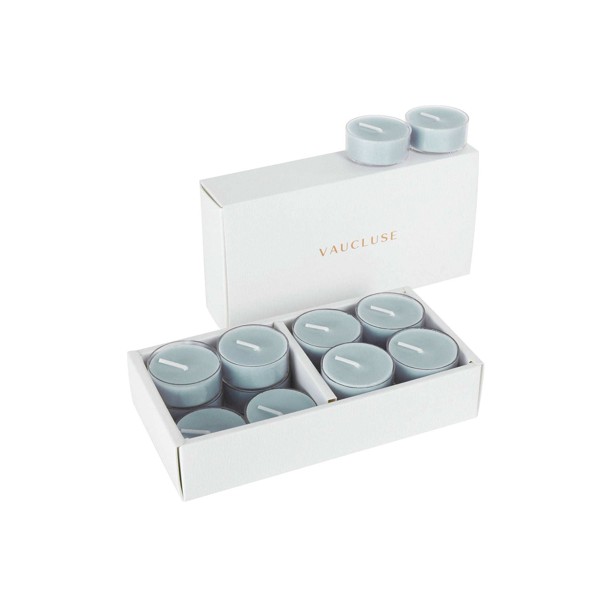 An open luxury white Vaucluse box set displaying premium grey blue velvet scented tealight candles arranged in a tiered 16-pack tray.