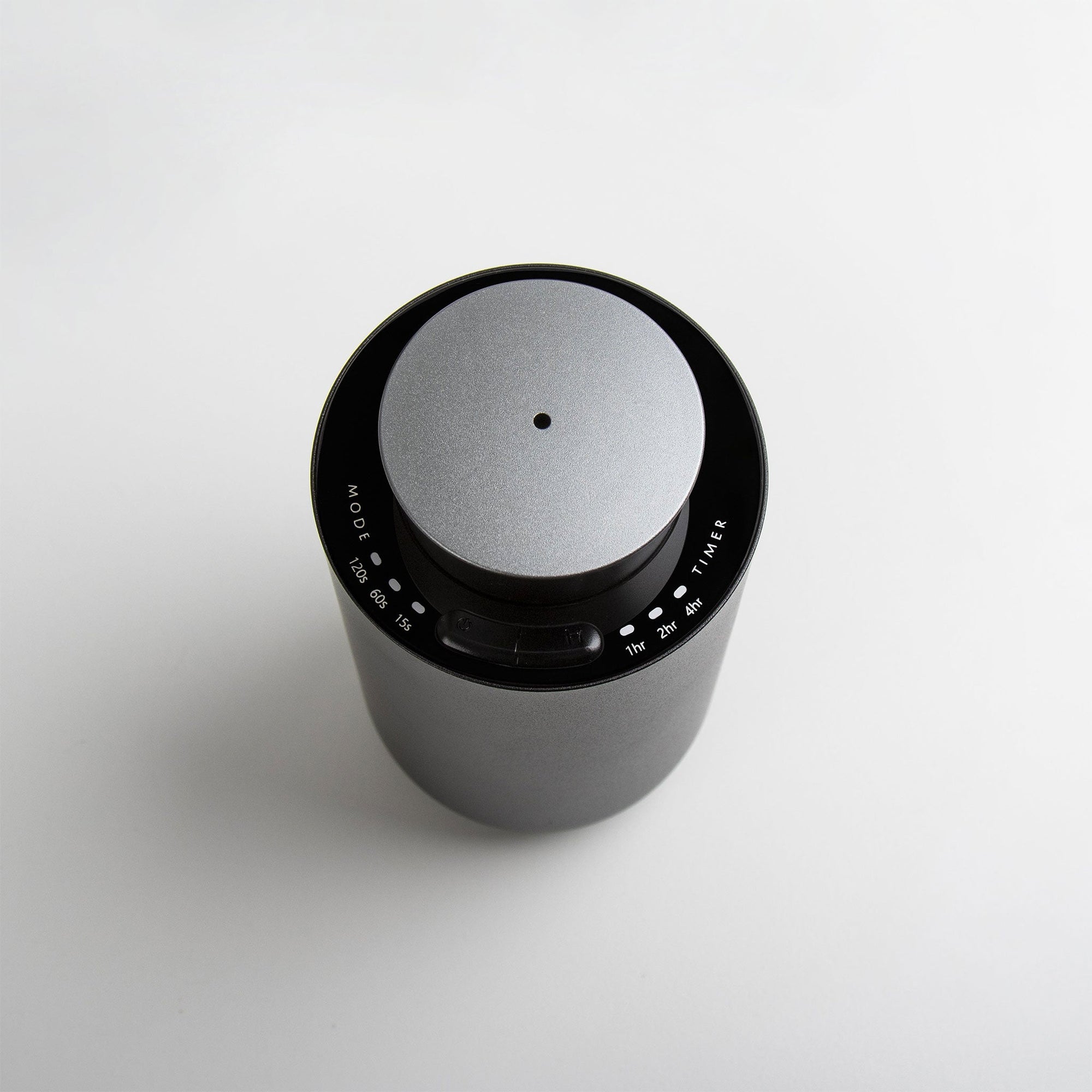 An overhead top-down view of the circular black and silver waterless diffuser highlighting its central mist nozzle and touch-sensitive interface.
