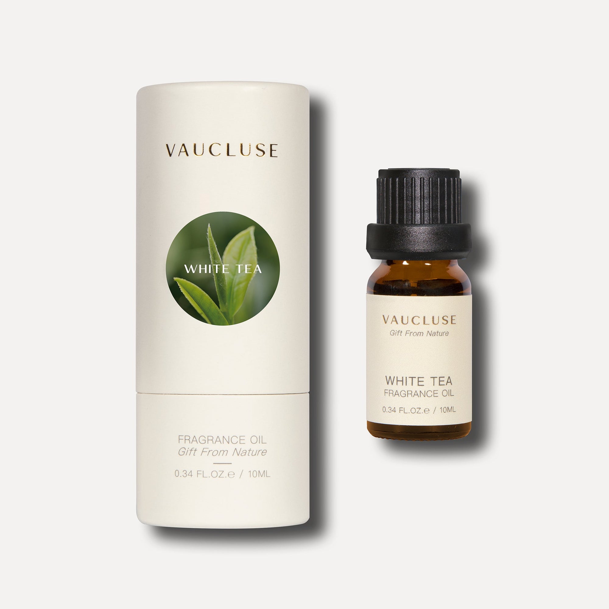 A 10ml bottle of white tea essential oil standing beside its white cylindrical tube box which displays a circular green leaf motif.
