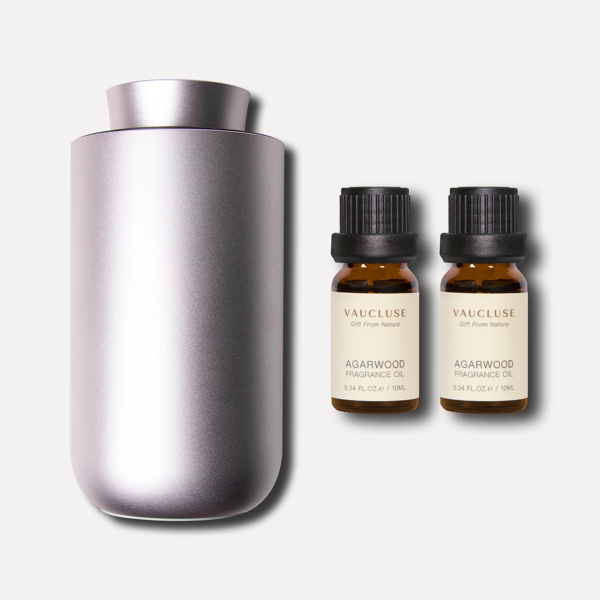 A sleek purple dusk waterless nebulizing diffuser shown alongside two 10ml amber bottles of premium agarwood essential oil.